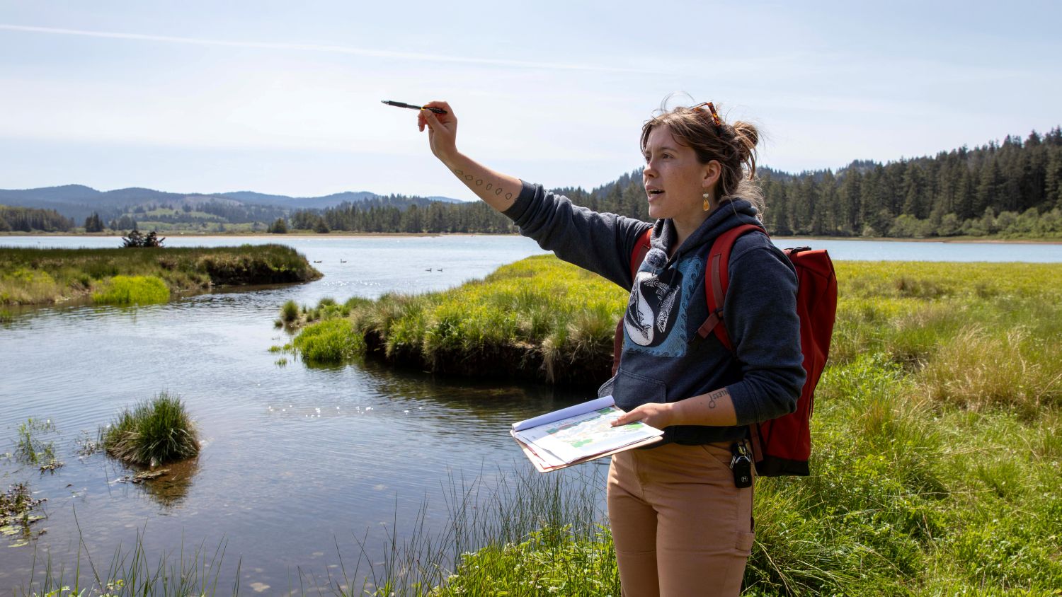 Guide holding maps and pen speaking about area at Salmon River Estuary.