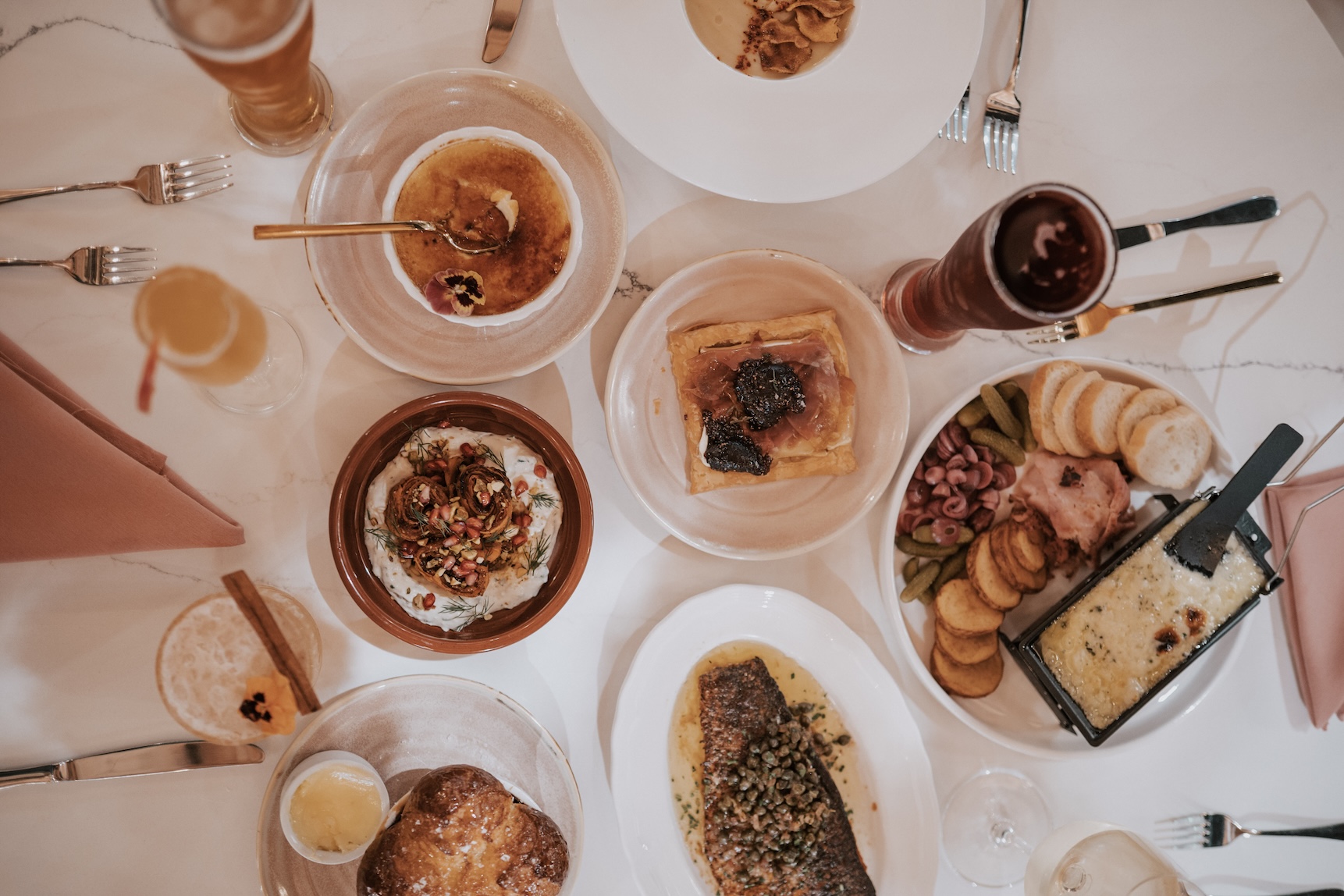 white linen tablecloth laid with multiple foods plated on white dishes