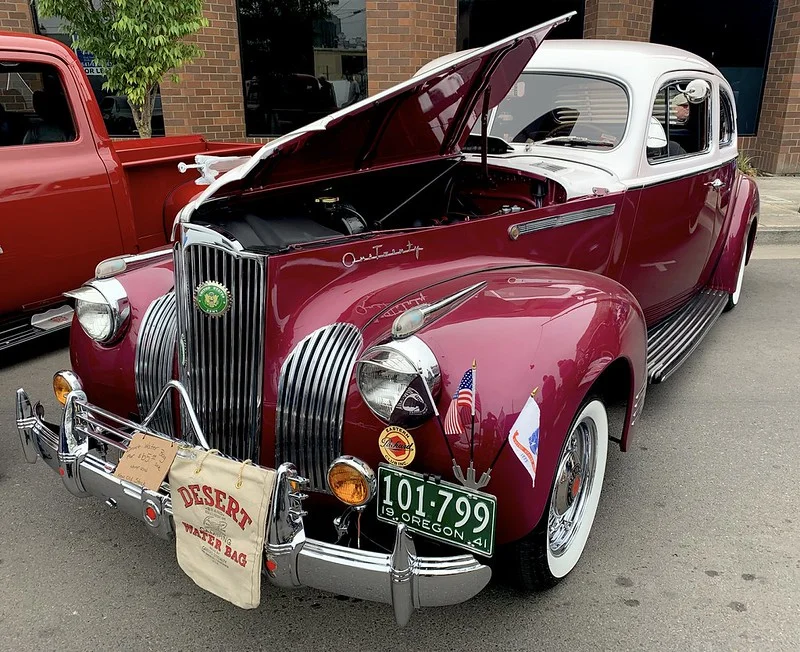 Antique burgundy vehicle with a white top and open hood.