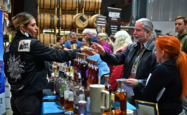 Person accepting sample from vendor at booth at Corvallis Spirits Festival