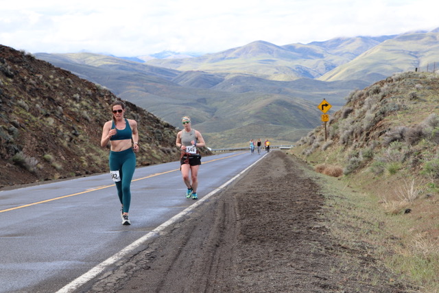 Two people running uphill at last year's Half Marathon Event. The runners are surrounded by rolling green hills.