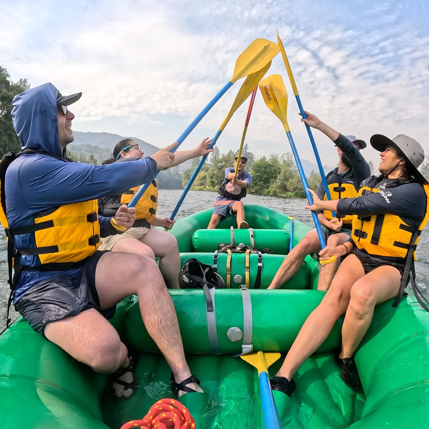 Five people in a paddle raft raising their paddles