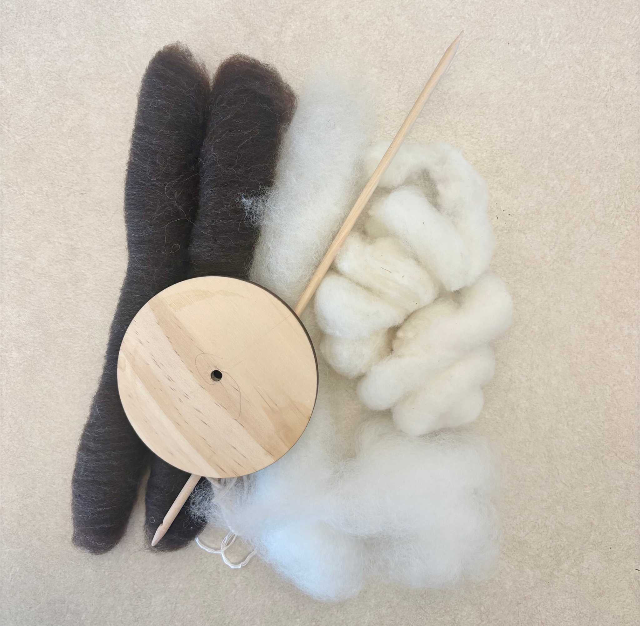 Two piles of handspun woll next to the tool used to spin the material