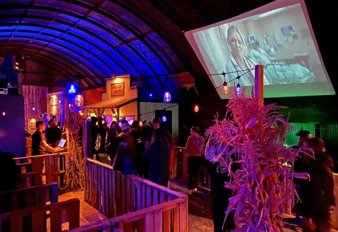 People watch a scary movie on a large projection screen at the Haunted Warehouse